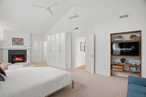 Modern bedroom with a fireplace, entertainment center, and vaulted ceilings, designed for relaxation.