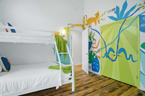 Children's bedroom with a bunk bed and jungle mural on the wall.