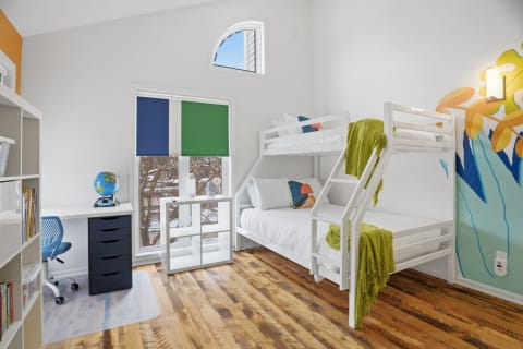 Colorful children's bedroom with a bunk bed, desk, and vibrant wall mural.