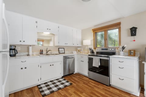 Modern kitchen featuring white cabinets, stainless steel appliances, and a marble countertop.