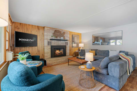 Interior view of a cozy living room featuring a fireplace, teal chairs, and a sectional sofa.