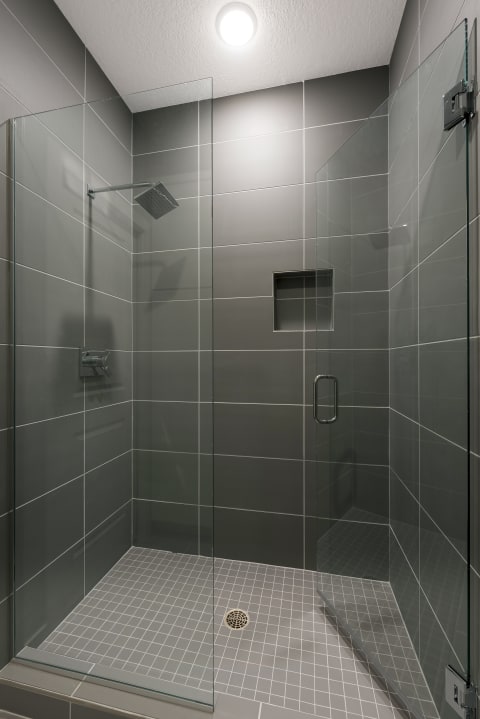 Contemporary shower with glass walls and gray tile flooring.
