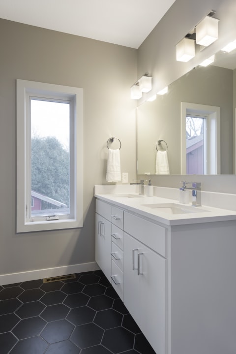 Contemporary bathroom with gray walls, white vanity, and black hexagonal tiles.