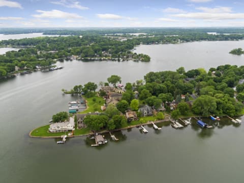 Aerial view of lush green peninsula with homes and boats along a lake.
