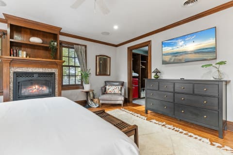 Warm and inviting bedroom with a fireplace, bed, and dresser.