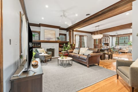 Cozy living room with a leather sofa, armchair, coffee table, and white-brick fireplace.