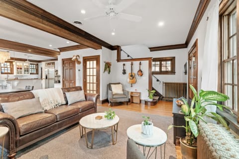 Warm living room featuring leather sofa, guitars on the wall, and plants.