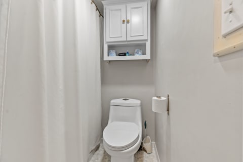 Small bathroom featuring a white toilet, wall-mounted cabinet, and clean design.