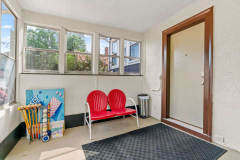 Bright sunroom featuring red chairs and a display of golf clubs.