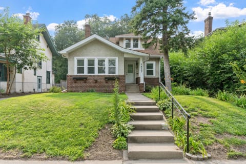 Exterior view of a charming house with a green yard and a staircase.