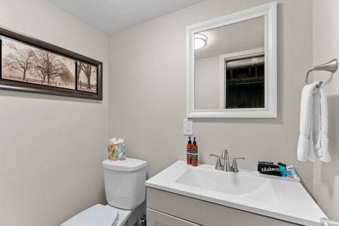 Modern bathroom with a clean design, featuring a white vanity, framed artwork, and neutral walls.