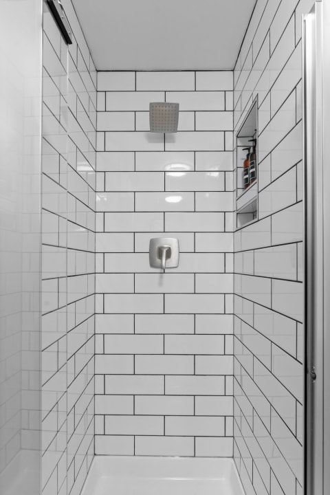 Modern shower featuring white subway tiles and a square shower head.