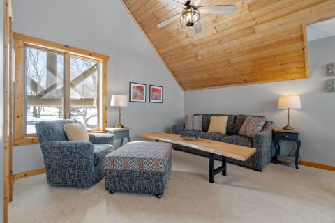 Cozy living room with wooden ceiling, a gray sofa, and a wooded coffee table.