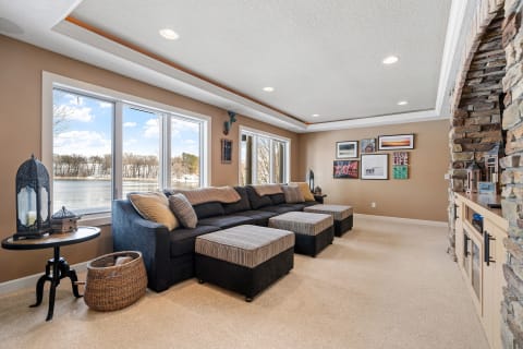 A warm living room with a sectional sofa and large windows overlooking a lake.