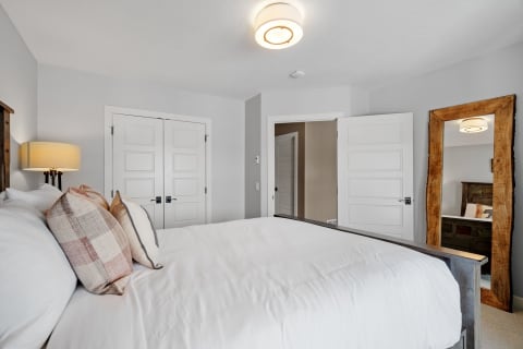 Cozy bedroom featuring a large bed, rustic mirror, and contemporary decor.