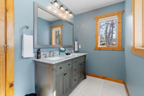 Bathroom interior featuring blue walls, a modern vanity, and natural wood accents.