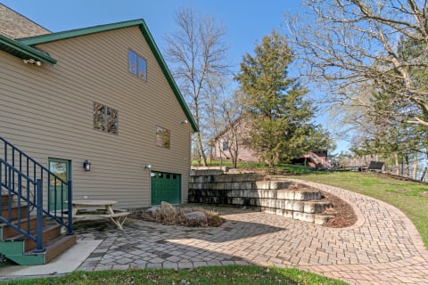 Modern home exterior with a brick pathway and picnic table in a landscaped yard.