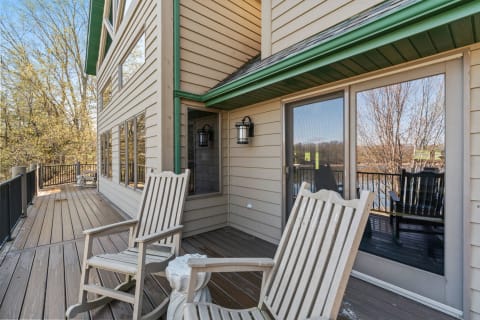 Outdoor deck with rocking chairs and a view of trees and water.