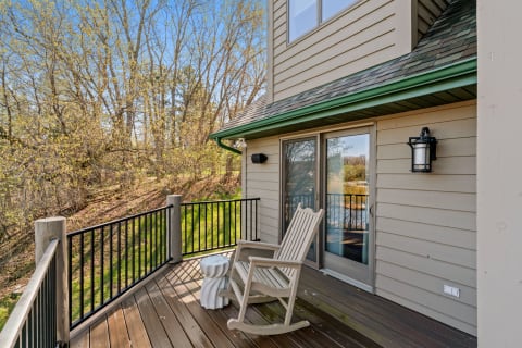 Balcony with a rocking chair, side table, and trees in the background.