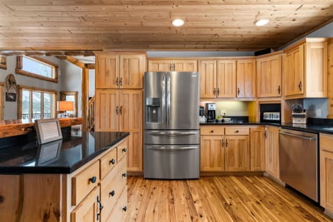 Interior view of a rustic kitchen with wooden cabinets and a stainless steel refrigerator.