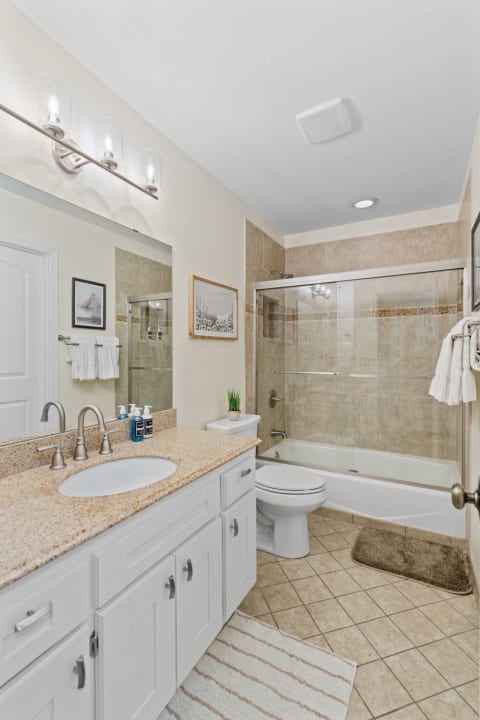 Modern bathroom with granite countertop, glass shower, and decorative elements.