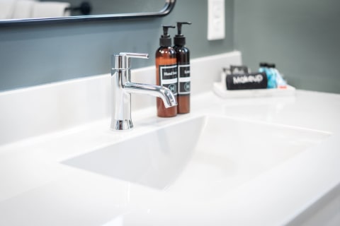 Modern bathroom sink with chrome faucet and amber soap dispensers
