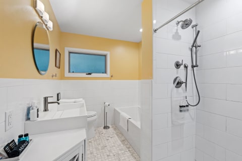 A contemporary bathroom featuring a yellow wall, a white vanity, and a shower area.