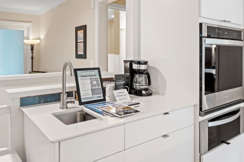 A pristine kitchenette with a sink, coffee maker, guest information sign, and decorative elements.