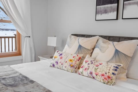 Stylish bedroom with floral pillows, snowy landscape outside, and modern decor.