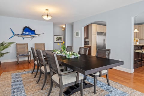 Modern dining room with a dark wooden table, colorful centerpiece, and a fish sculpture on the wall.