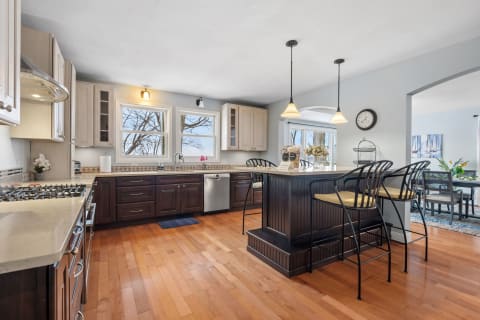 Modern kitchen with rich brown cabinetry, light countertops, and a breakfast island with bar stools.