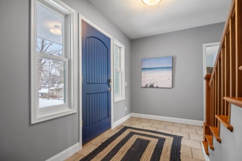 Entryway with a navy front door and beach scene on the wall.