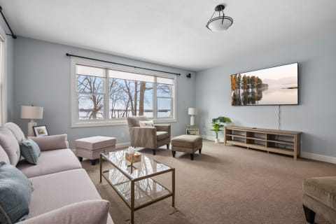 Modern living room featuring lake views through large windows and stylish furniture.