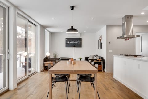 Contemporary kitchen and dining space with a wooden table, black chairs, and large windows.