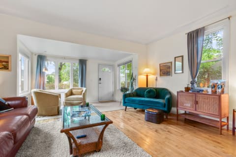 Cozy living room with a leather sofa, teal sofa, and large windows.