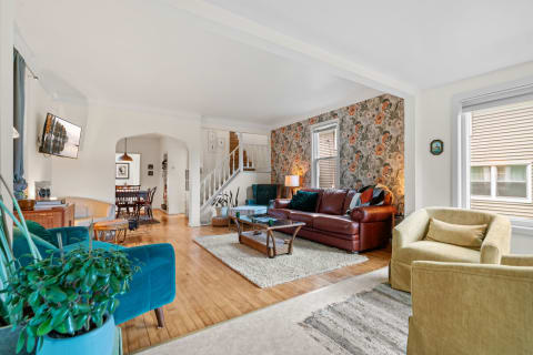 Inviting living room with floral wallpaper, leather sofa, and a dining area.