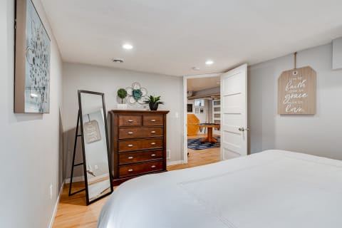 Cozy bedroom with a mirror and a dresser, showcasing soft lighting and minimalist decor.