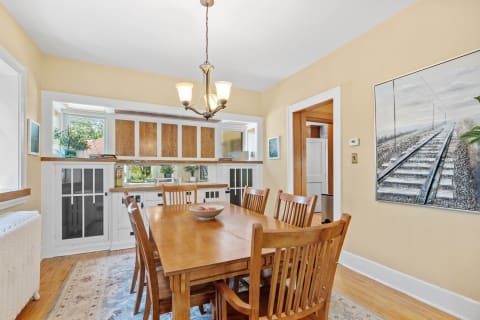 A warm dining room featuring a wooden table, chairs, and a chandelier.