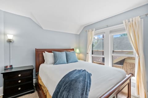 Cozy bedroom featuring a wooden bed, blue cushions, and soft lighting.