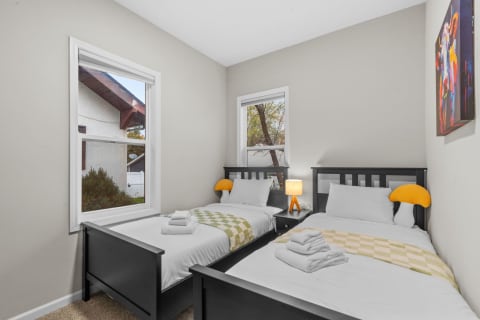 Cozy bedroom featuring two twin beds with a colorful abstract painting on the wall.