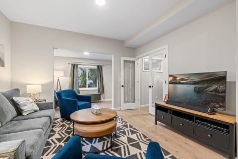 Modern living room with gray sofa, blue chairs, and a large window.