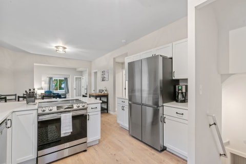 Modern kitchen with white cabinets, stainless steel refrigerator, and a clean countertop.