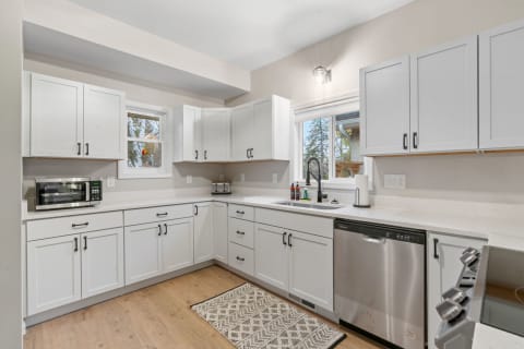 A modern kitchen featuring white cabinets, a stainless-steel sink, and a cozy rug.
