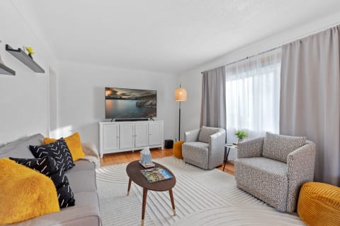 A cozy modern living room with gray sofa, geometric armchairs, and a wooden coffee table.
