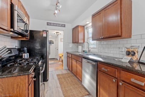 Interior view of a cozy kitchen with wooden cabinets, black appliances, and a welcoming atmosphere.