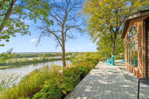 A wooden deck overlooking a calm river surrounded by trees and autumn colors.