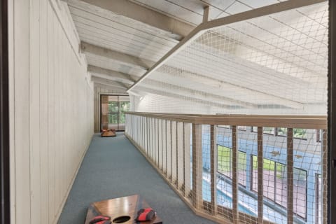 Indoor balcony with wooden beams, safety net, and cornhole boards.