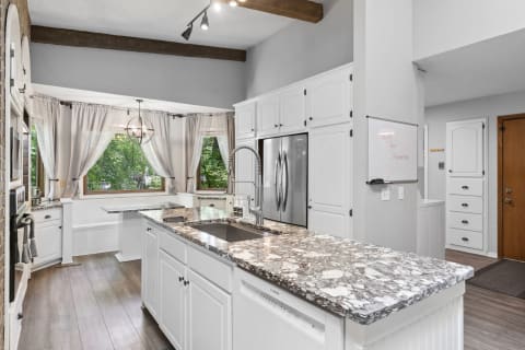 Modern kitchen featuring an island with granite countertop and white cabinets.