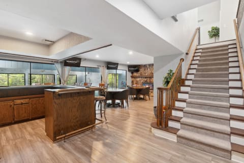 Interior view of a modern living space with a bar, dining area, and staircase.