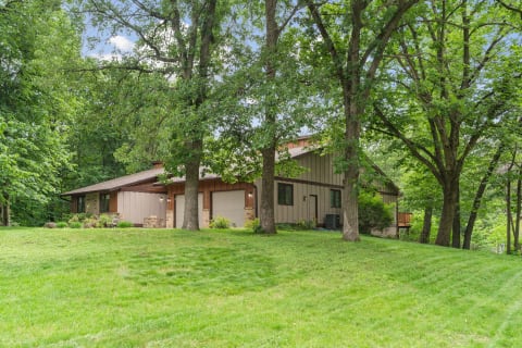 A contemporary house with a brown façade set in a green, wooded area.